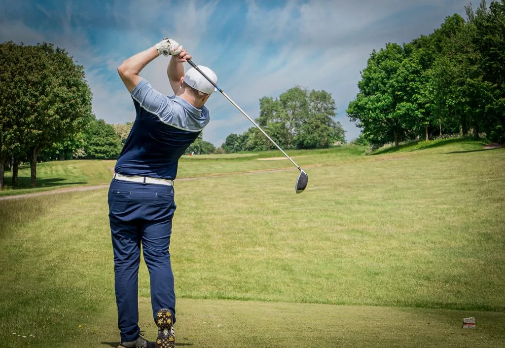 A man in backswing watching the flight of his golf ball at Wycombe Heights Golf Club in High Wycombe
