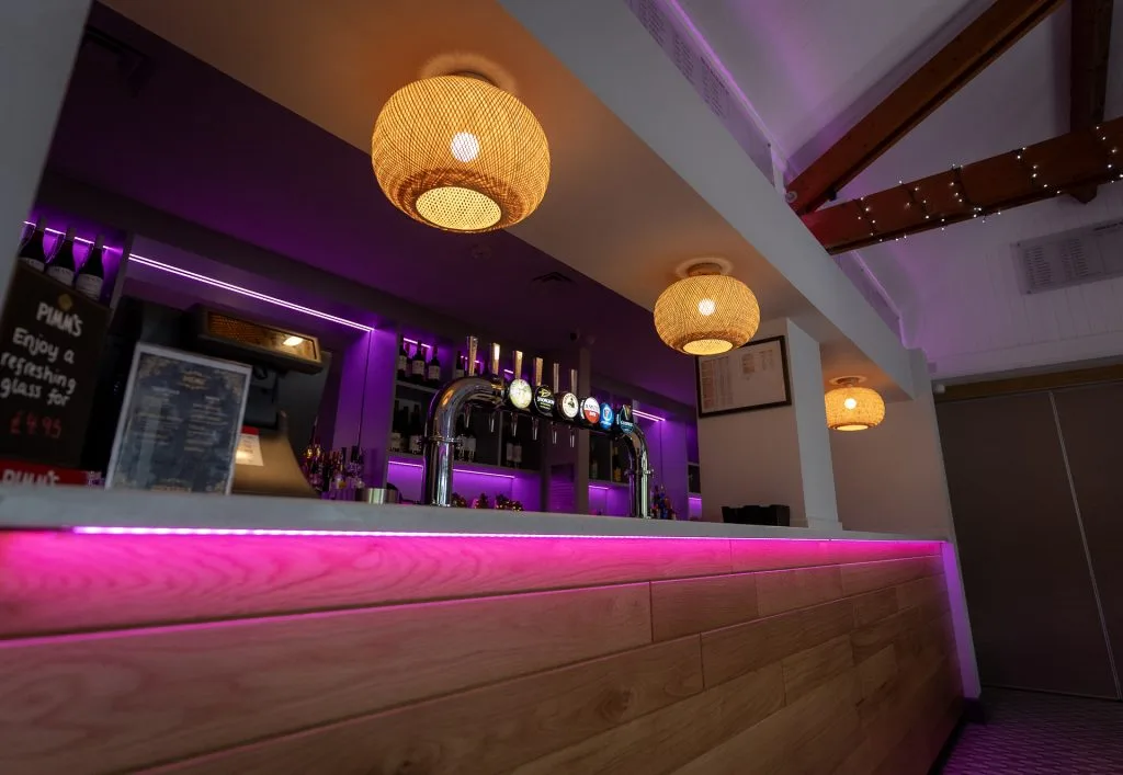 A modern bar with pink lighting inside the Wycombe Heights events venue in High Wycombe